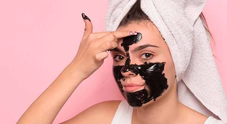 Tutto quello che c’è da sapere sui pori dilatati del viso Ragazza che distende maschera nera sul viso