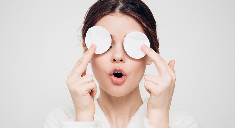 Ragazza che si mette dischetti struccanti sugli occhi