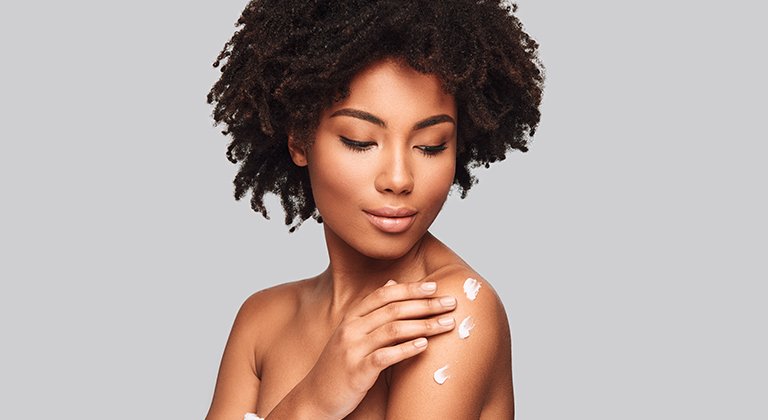 Donna che si spalma crema sulle spalle